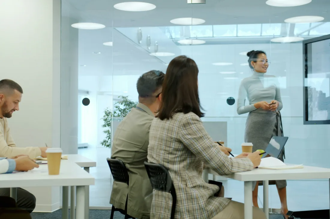 A colleague presenting to a seated team in a bright modern meeting room.
